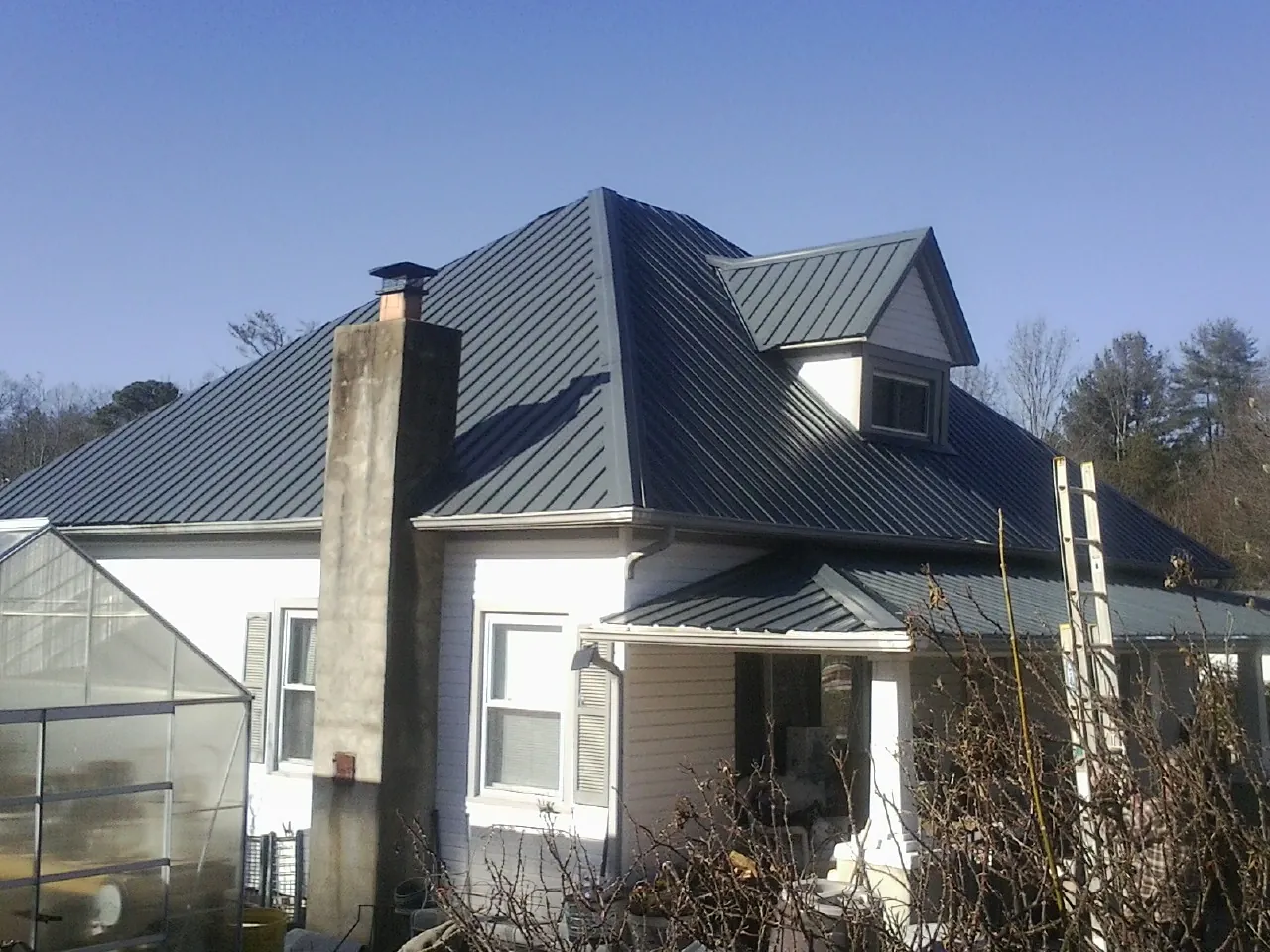 Dark blue standing seam metal roof on a white farmhouse with dormer — Slate & Tile Roof Repair by Roofing Brothers in Rescue