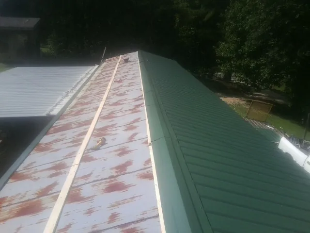 Old rusted panels beside newly installed green metal roofing — Wind Damage Roof Repair by Roofing Brothers in Rescue