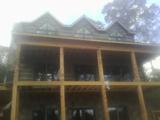 Dormers and porch framing on a large log home under construction — Roof Coating work by our crew in Rescue