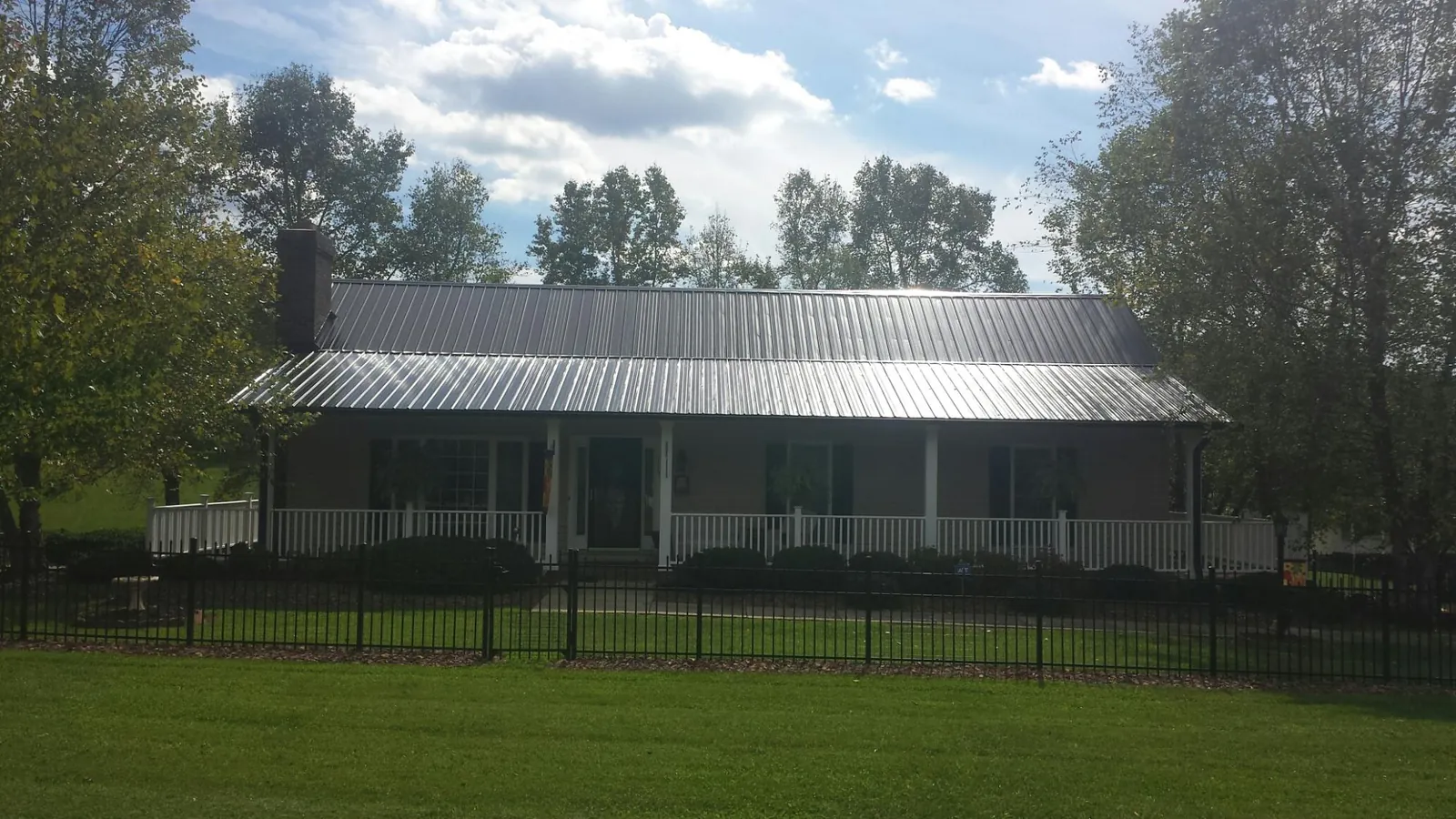 Gray metal roof on a brick ranch with a full width front porch — Gutter Guard Installation work by our crew in Rescue