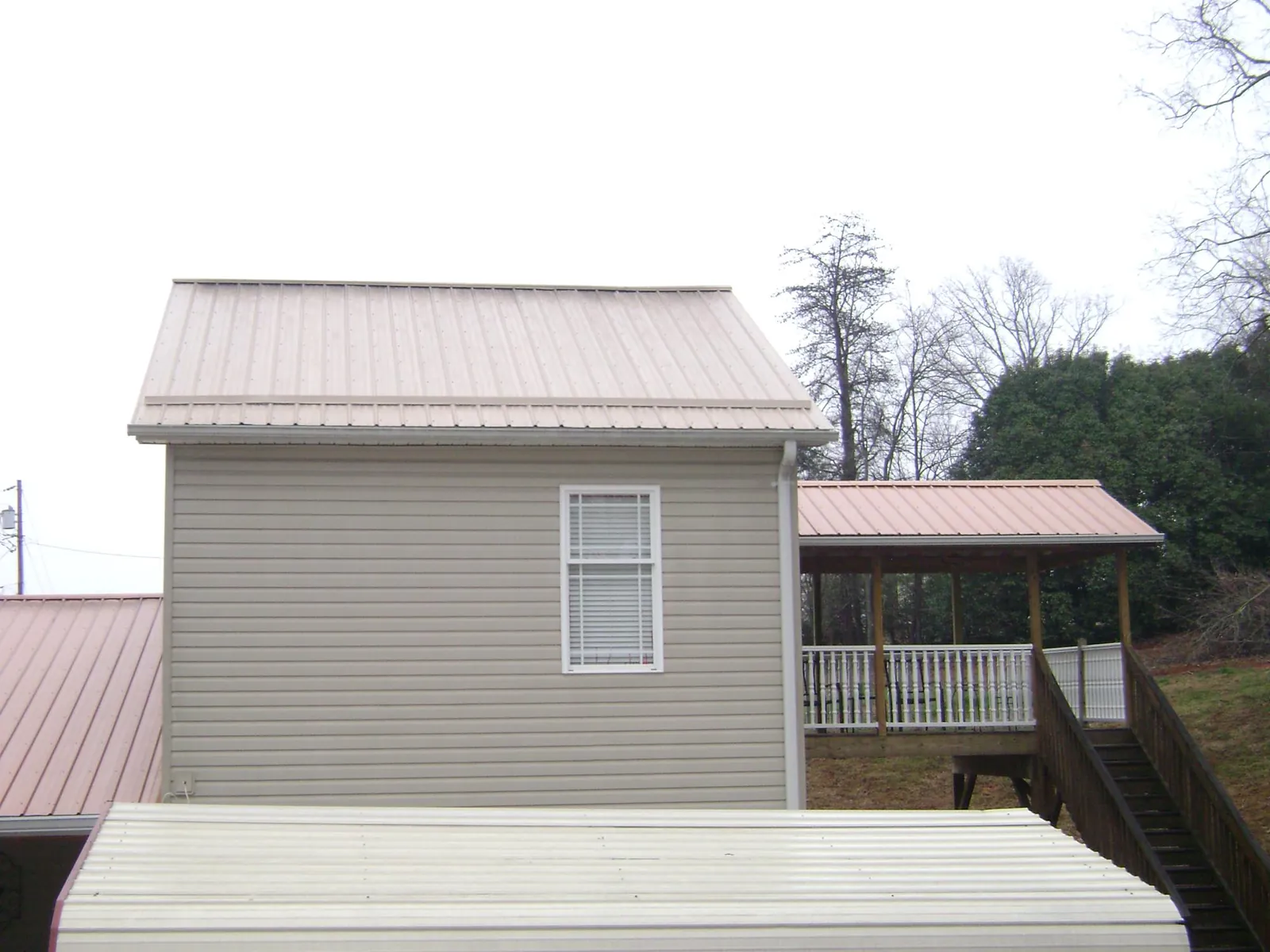 Tan metal roofs on a two story addition and attached porch, from a Roof Replacement job in Rescue